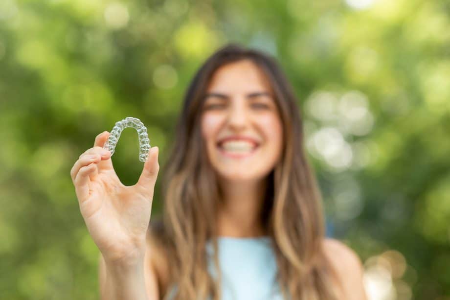 woman holding invisalign retainer in front of her